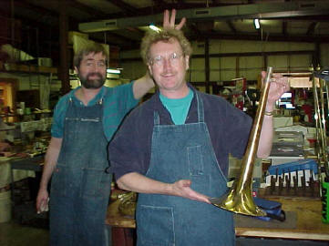 co-worker giving Scott bunny ears as he shows trumpet piece