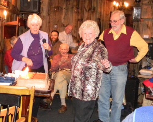 Carol at cake with fiery candles, all smiling