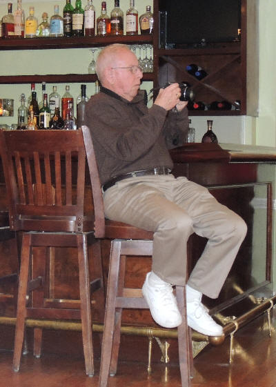 Harold on a high stool by the bar, videotaping the band