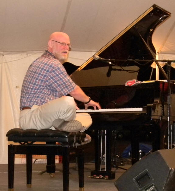 Jeff sitting with his legs crossed on the piano bench