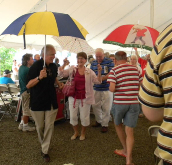 Bob with yellow and blue umbrella followed by crowd