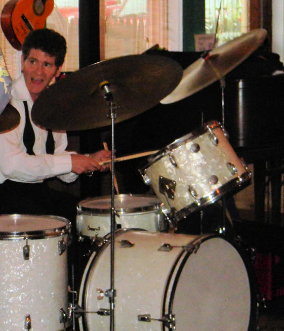 Robbie with bow tie hanging down, playing on drum