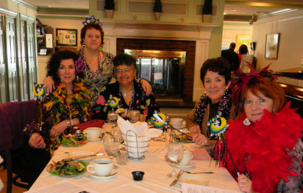 5 ladies dressed in Mardi Gras colors, boa